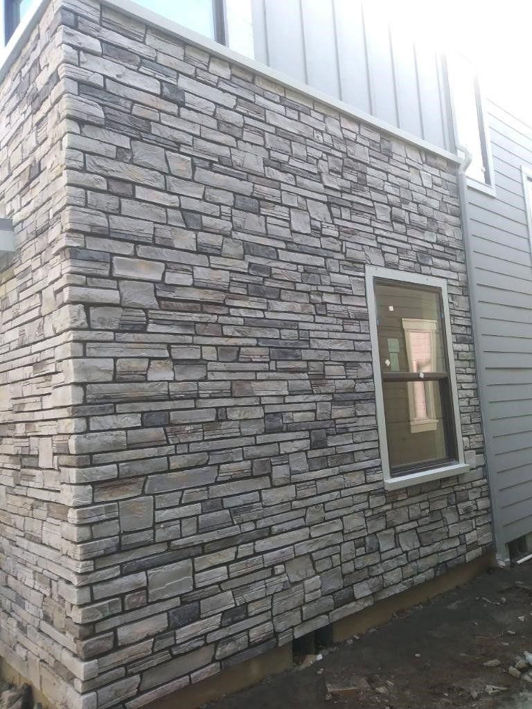 Stone veneer exterior wall with a small window and bright sunlight above the roofline