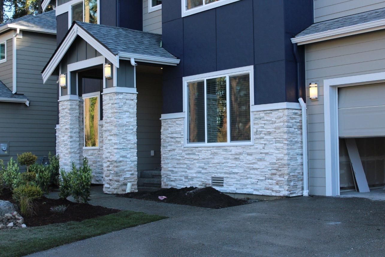 Modern house exterior with blue siding, stone accents, and a garage doorway
