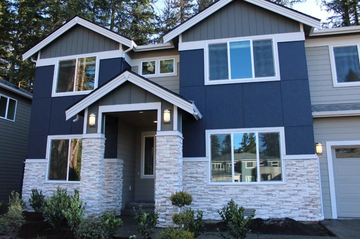 Front view of a blue-and-white two-story house with stone columns and a covered entryway.