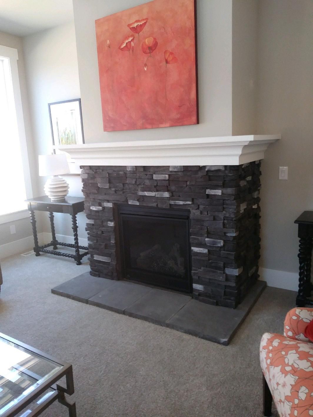 Living room fireplace with dark stone surround, white mantel, and a coral painting above it