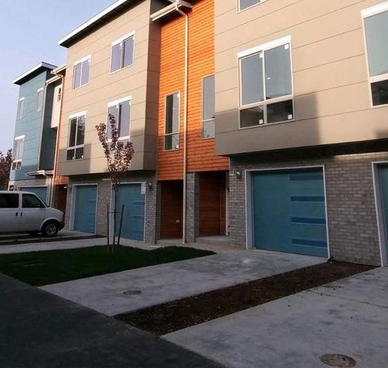 Row of modern townhouses with blue garage doors and a parked white van