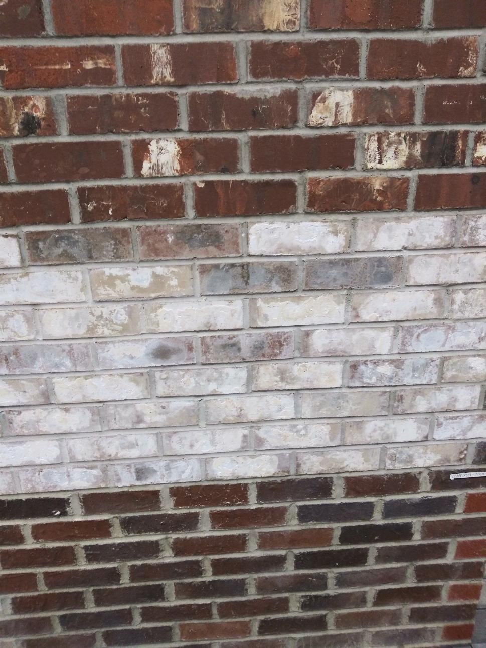 Brick wall with a faded whitewashed middle section and darker red brick at the top and bottom.