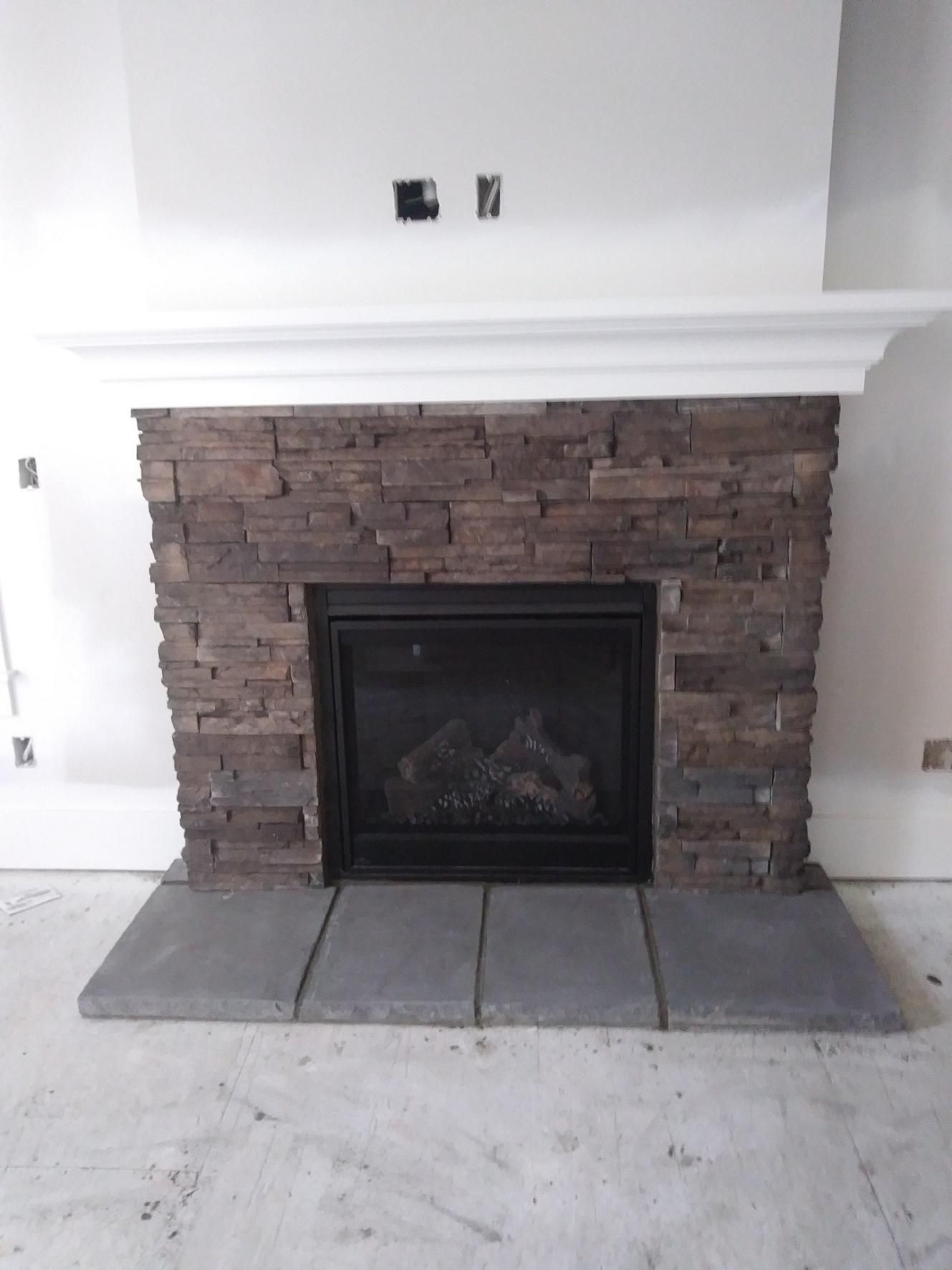 Brick fireplace with black insert and stone hearth in a white room.