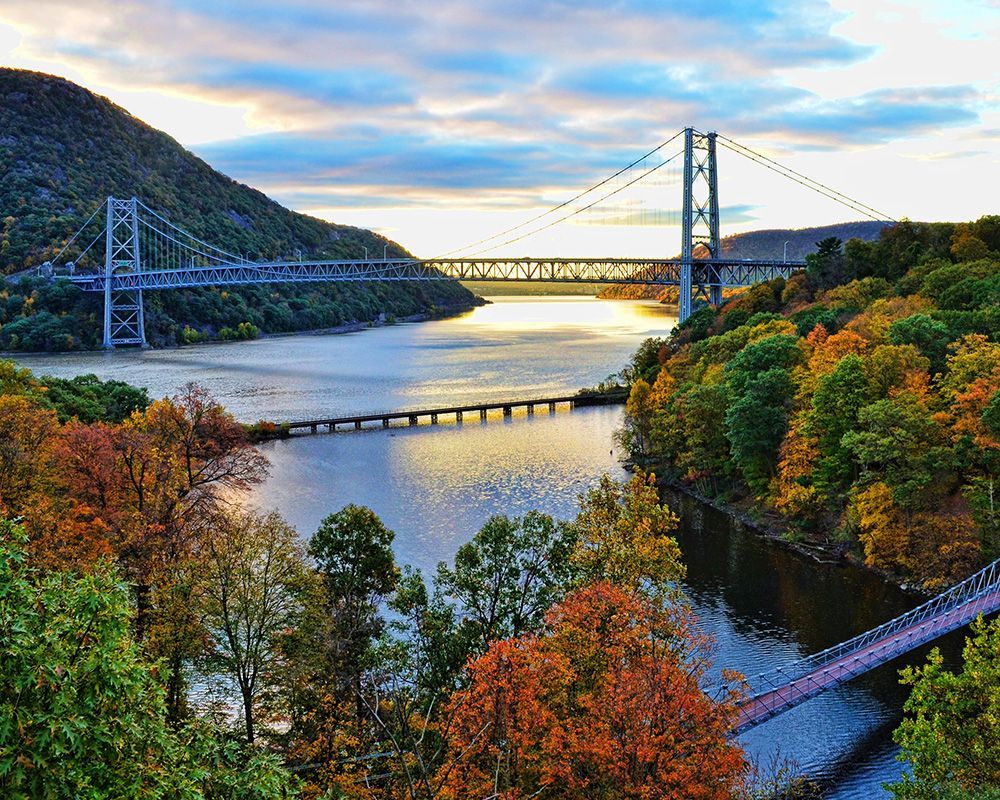 A bridge over a river surrounded by trees and mountains.