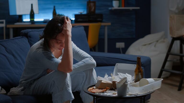 A woman is sitting on a couch with her head in her hands.