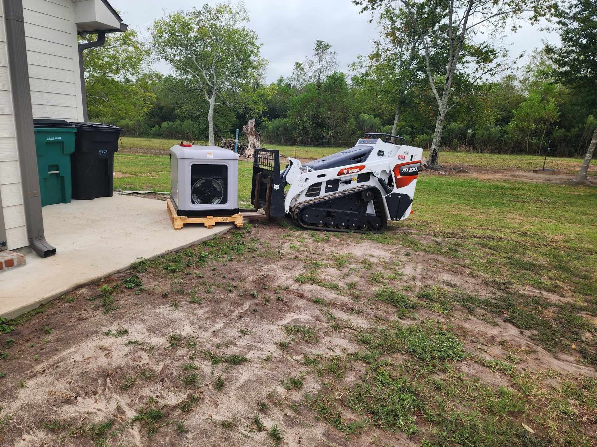 Overturned white utility vehicle beside a house, with a tipped appliance on the grass and muddy yard.