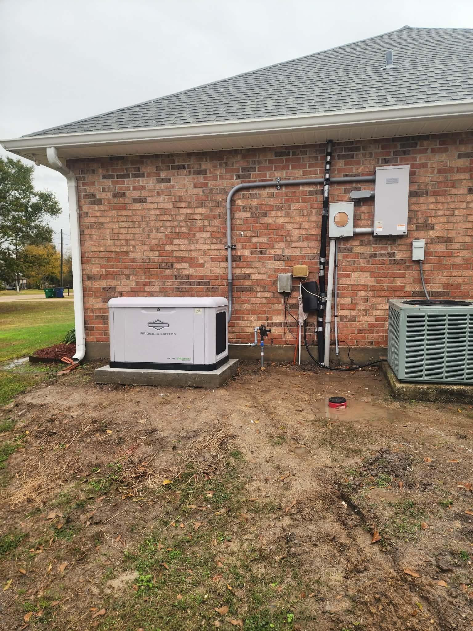 Backyard utility area with HVAC units and exposed pipes beside a brick house