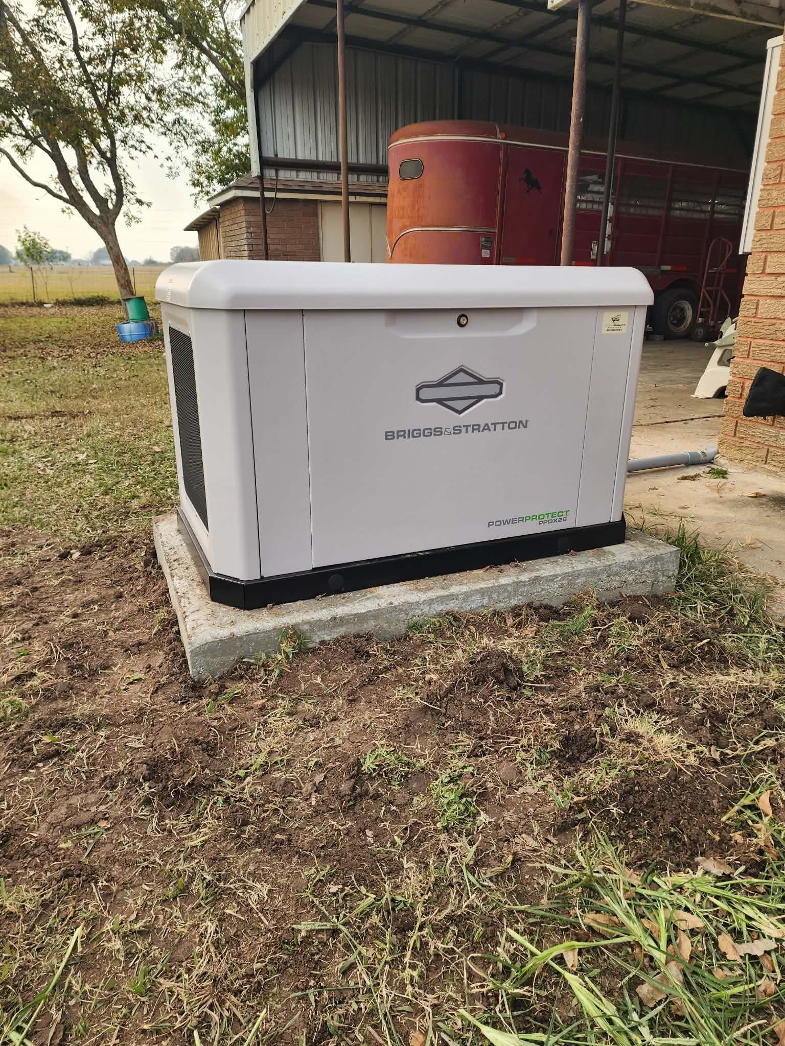 White generator cabinet outdoors beside red tanks under a metal shed.