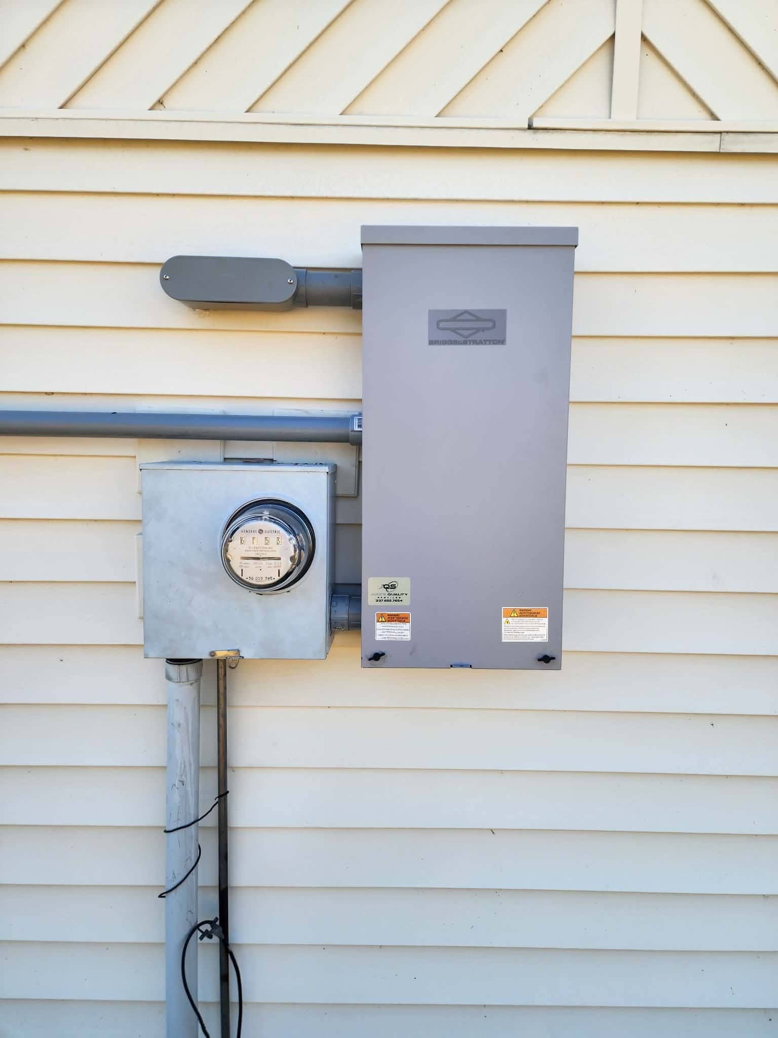 Electric meter and gray utility box mounted on a beige house exterior