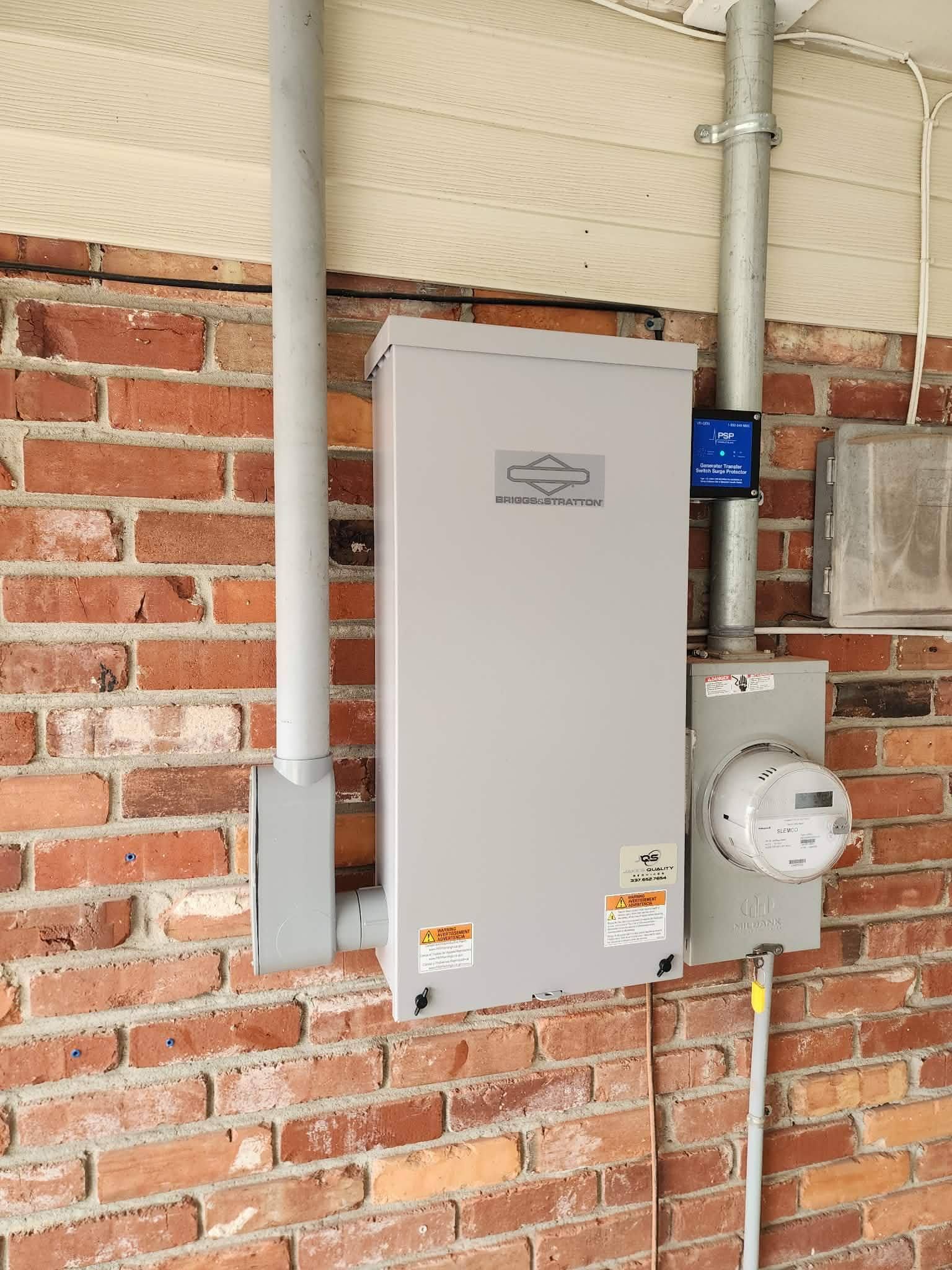 Gray electrical panels and utility meters mounted on a brick wall indoors.