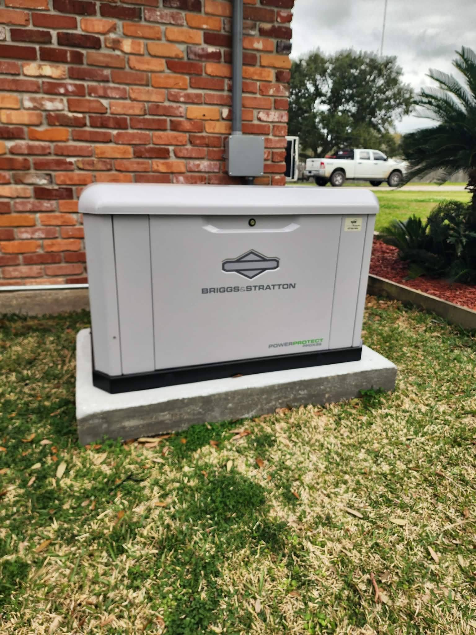 White utility box beside a brick wall on a lawn, with a logo and palm trees in the background