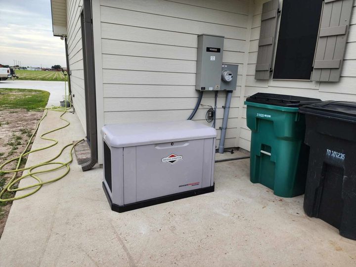 Gray storage box on a concrete patio beside utility meters and green trash bins
