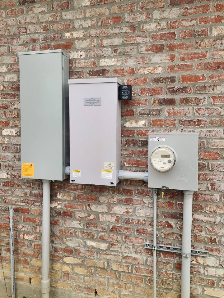 Three gray electrical utility boxes and a meter mounted on a brick wall