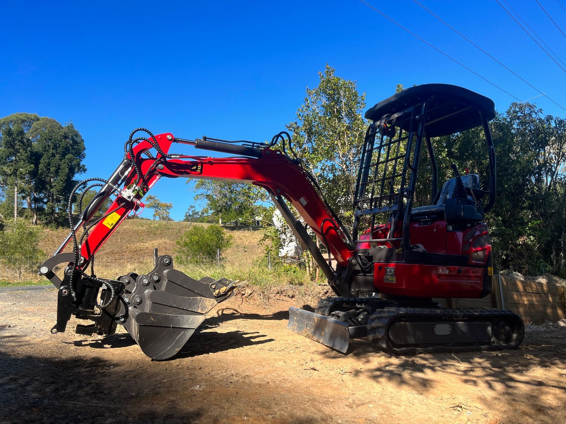 A Small Red Excavator Is Parked on The Side of The Road — ZBM Constructions in Wollongbar, NSW