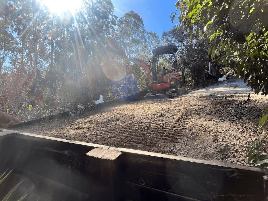 A Red Excavator Is Moving Dirt on A Dirt Road — ZBM Constructions in Alstonville, NSW