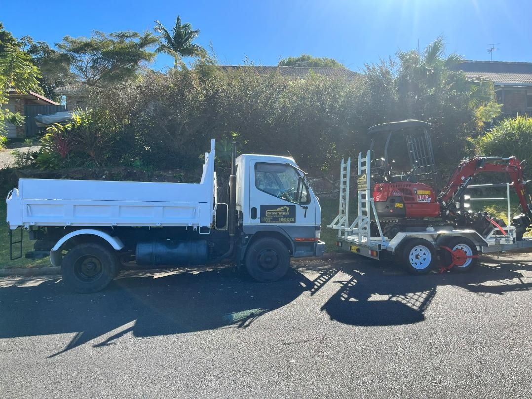 A White Dump Truck Is Parked Next to A Red Excavator on The Side of The Road — ZBM Constructions in Alstonville, NSW