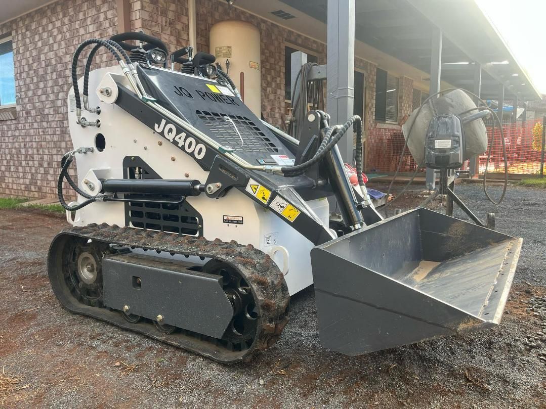 A White Skid Steer Is Parked in A Dirt Field — ZBM Constructions in Wollongbar, NSW