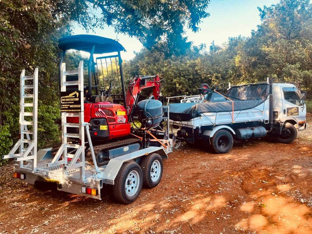 A small tractor is being towed by a truck on a trailer — ZBM Constructions in Wollongbar, NSW