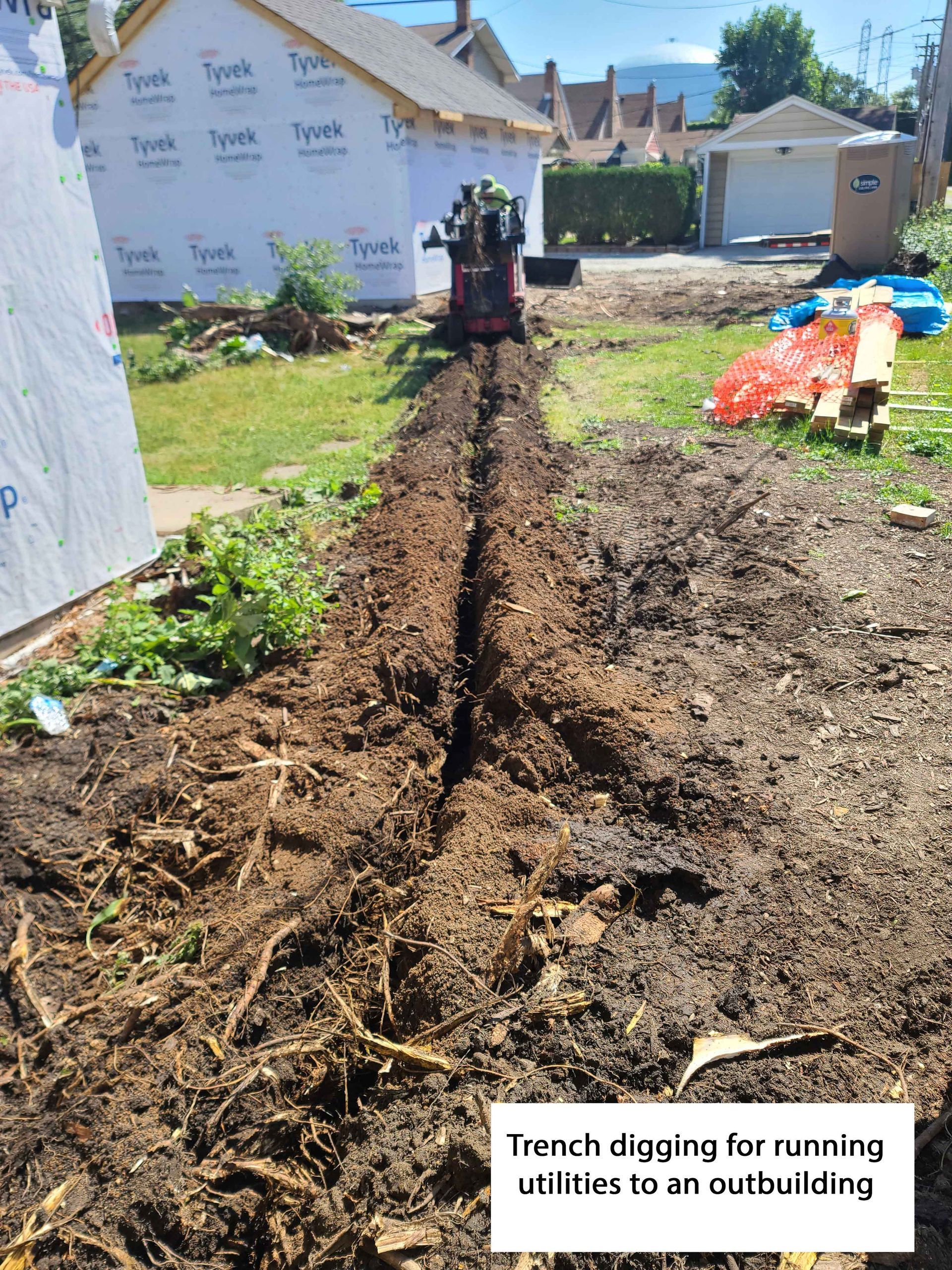 Trench dug in yard for utilities to outbuilding, with mini excavator.