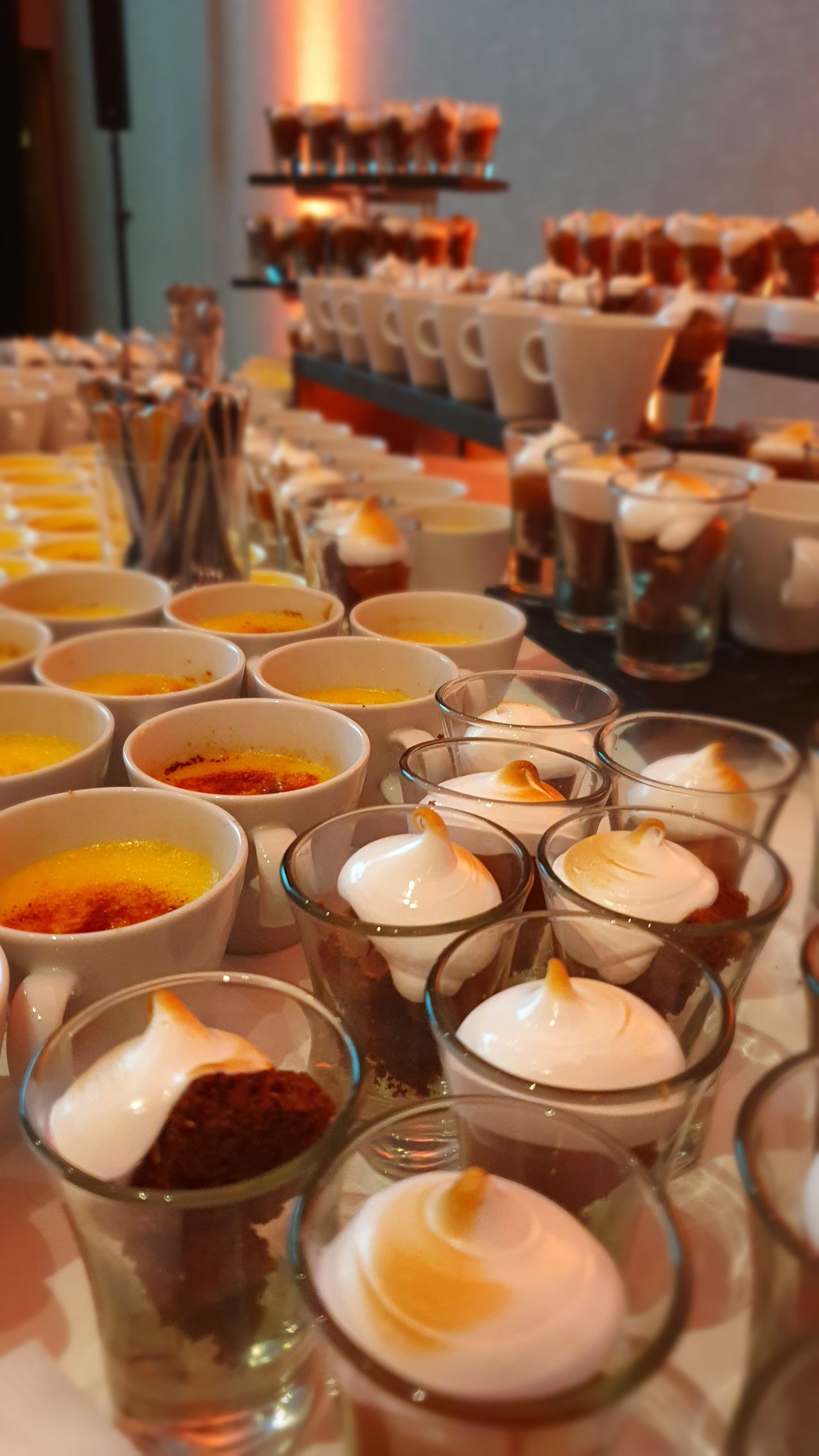 Una mesa de buffet con una variedad de postres en vasos de chupito