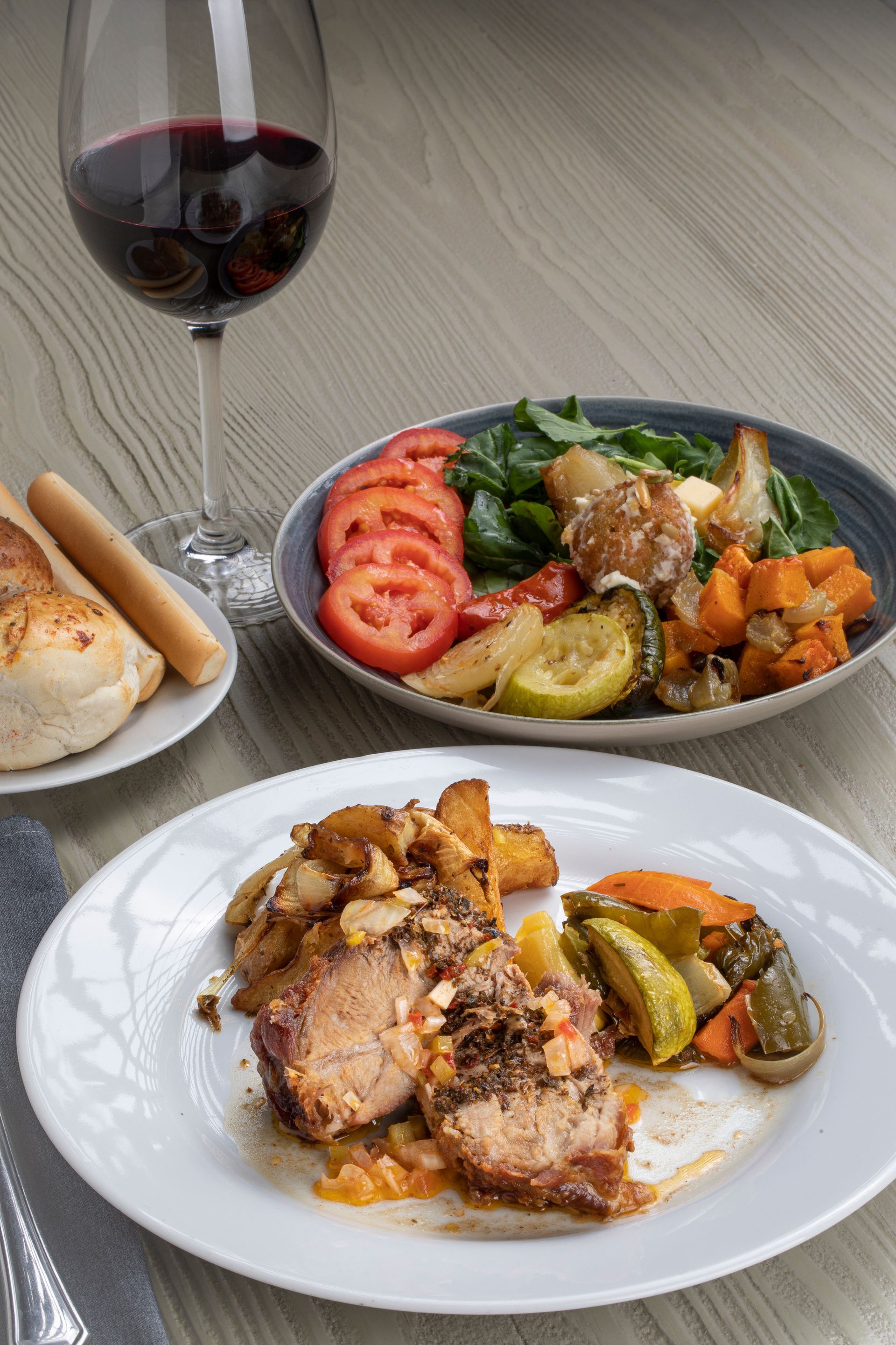 Un plato de comida y una copa de vino sobre una mesa.