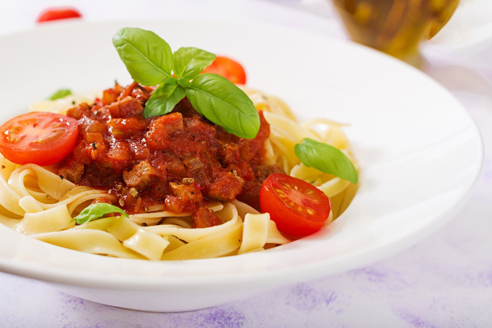 Un plato blanco cubierto con fideos, tomates y salsa de carne.