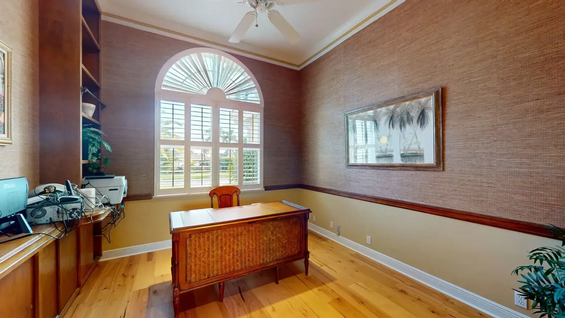 Spacious living room with light hardwood floors, high ceilings, a tan sofa and armchair, and large glass sliding doors that open to a covered patio with a waterfront view.
