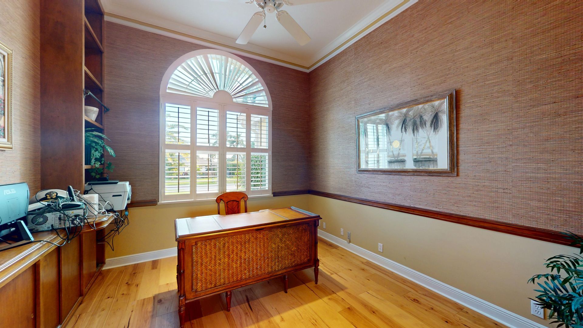 Spacious living room with light hardwood floors, high ceilings, a tan sofa and armchair, and large glass sliding doors that open to a covered patio with a waterfront view.