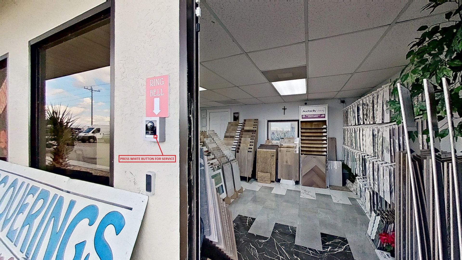 The front entrance of Floorcoverings & More Inc., featuring large signage outside, a glass door with a logo, and a view into the tile and flooring showroom.