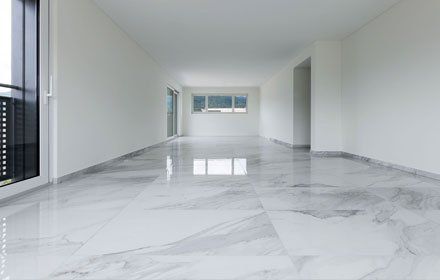 Empty, modern room with white walls, large windows, and glossy marble flooring.