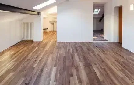 Spacious room with wood floor and white walls. Natural light from skylights.