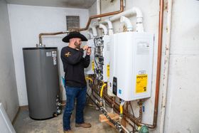 Technician inspecting a water heater and plumbing system in a utility room