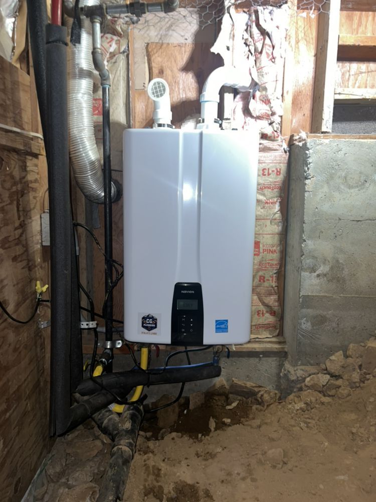 A white tankless water heater mounted on a wooden wall in an unfinished basement or crawl space.