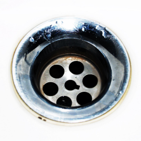 Close-up of a shiny chrome sink drain with a circular strainer hole pattern.