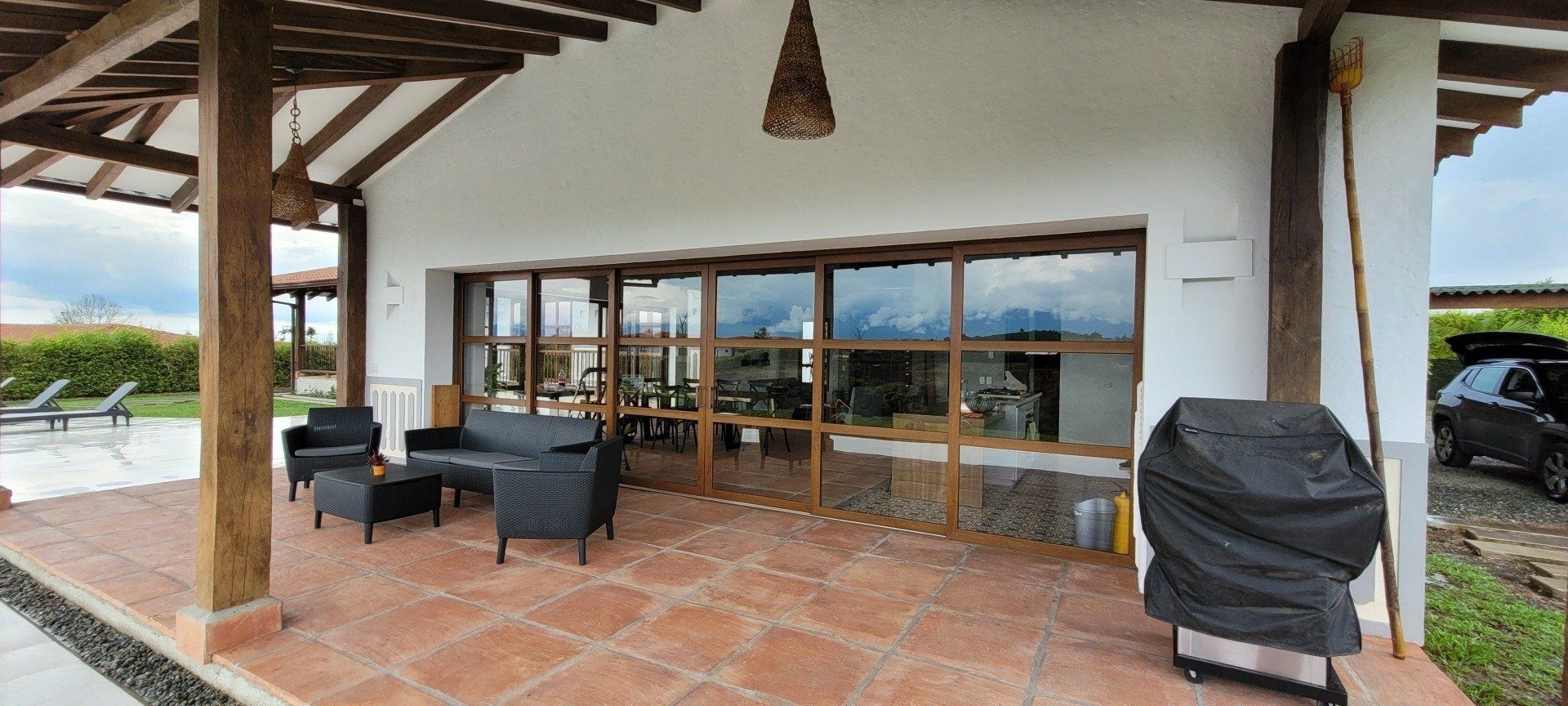 Un patio con parrilla y un sofá y sillas frente a una casa.