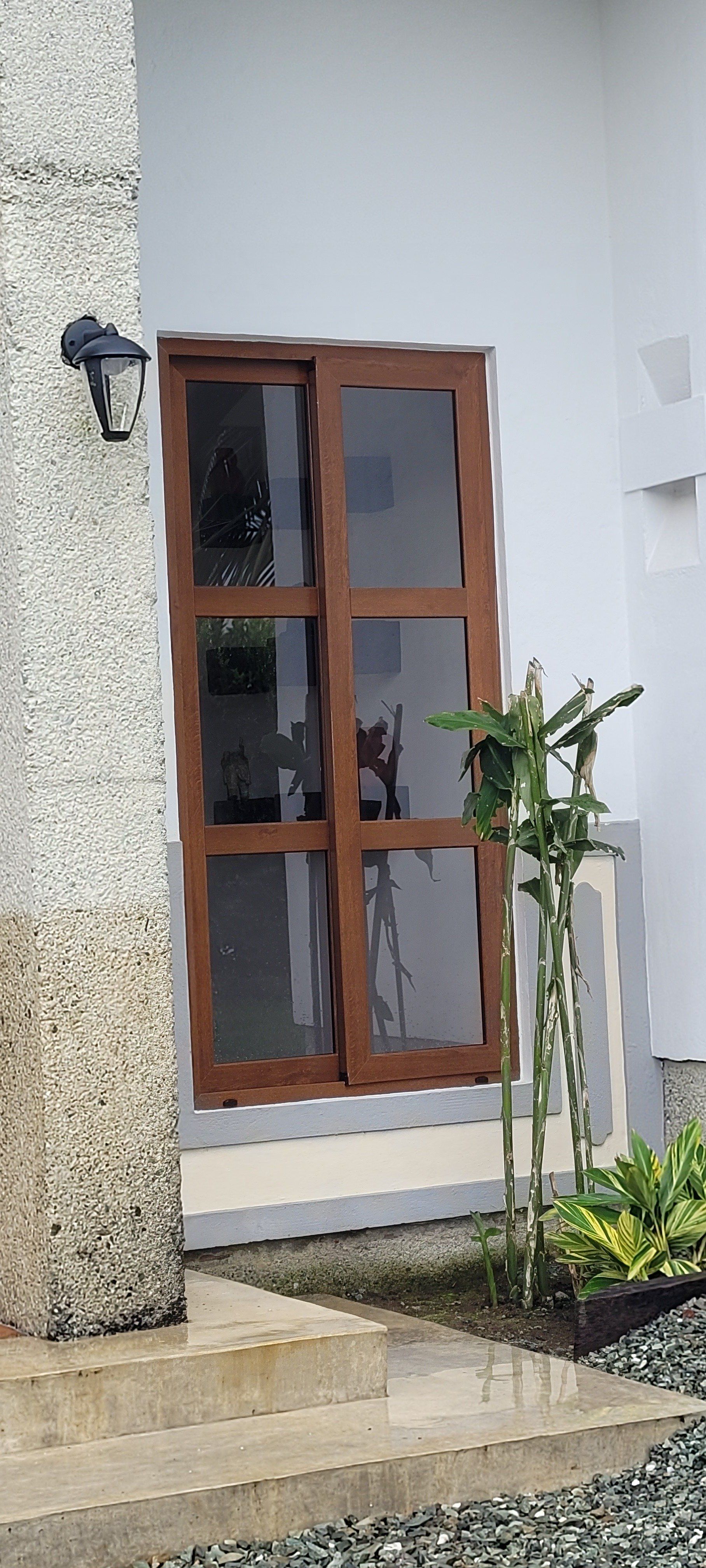 Un edificio blanco con una puerta de madera y una lámpara en el costado.