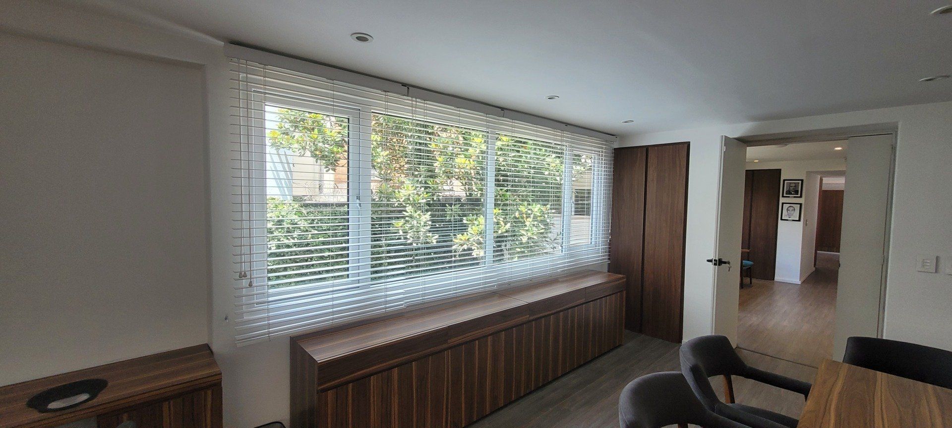 Una sala de estar con un gran ventanal y una mesa y sillas de madera.