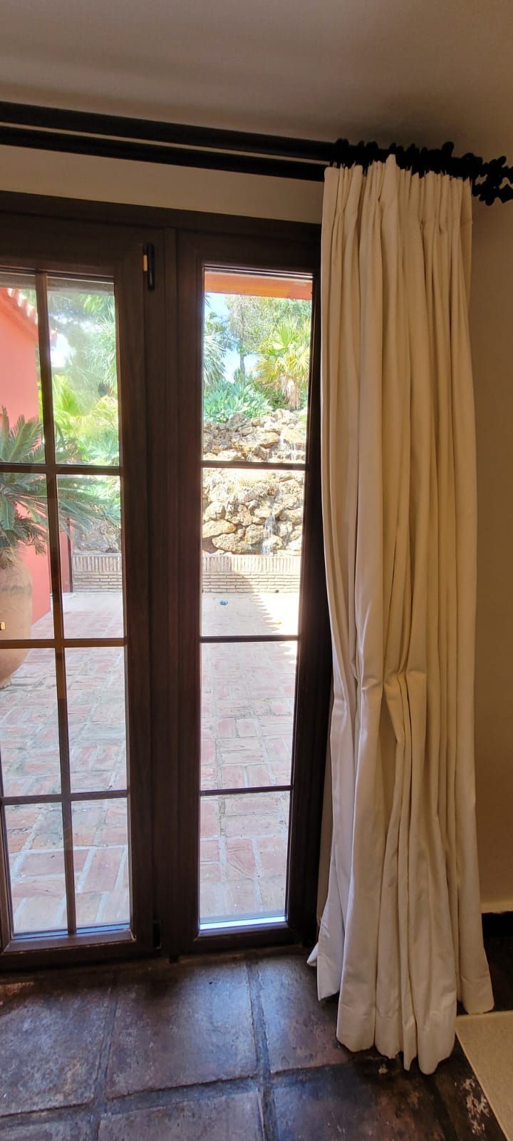 Una habitación con una puerta corrediza de vidrio y cortinas blancas.