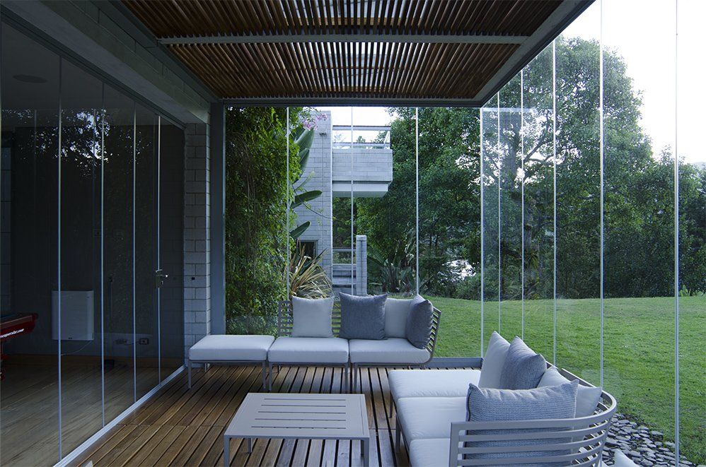 Un patio con un sofá y una mesa frente a una pared de vidrio.