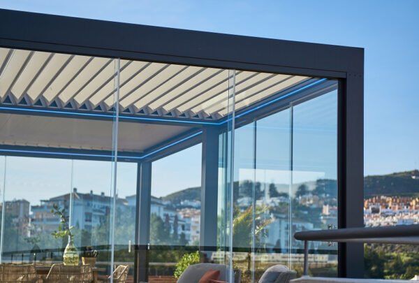 Una persona está sentada bajo una pérgola con puertas corredizas de vidrio.