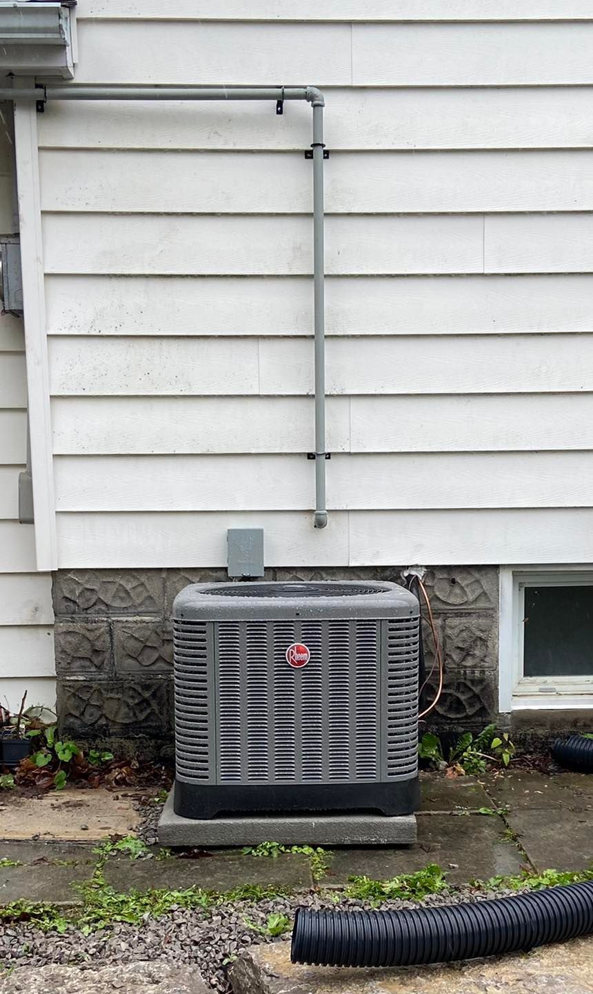An air conditioner is sitting on the side of a house next to a window.