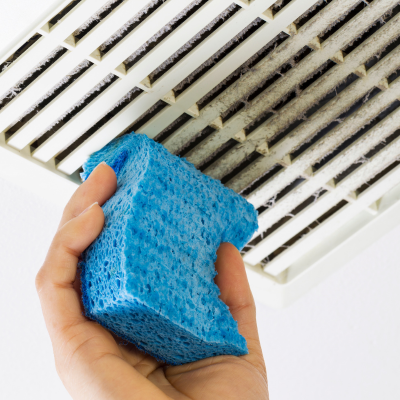 a person is holding a blue sponge in front of an air vent