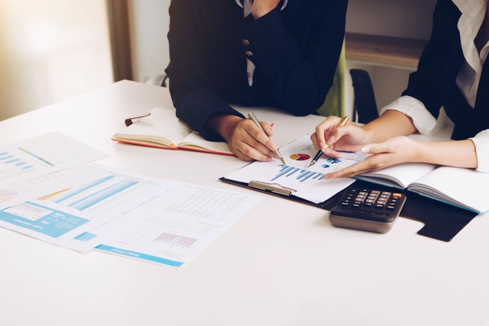 Two People in Suits Reviewing Charts, Using a Calculator, at a Desk — Cape York Accounting Smithfield in Cooktown, QLD