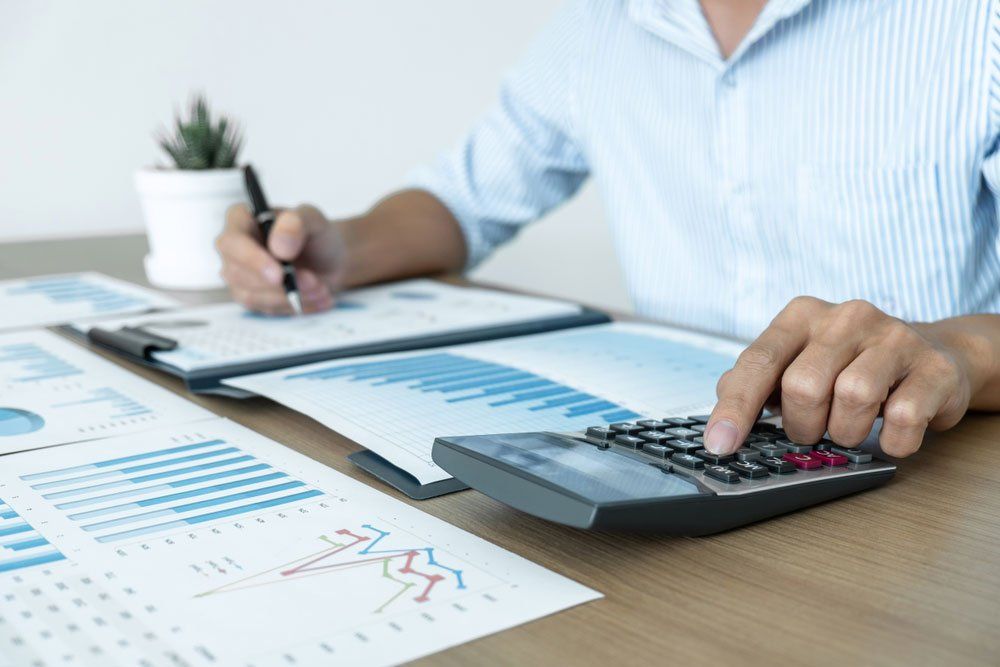 A Man Is Using a Calculator While Writing on A Clipboard — Cape York Accounting Smithfield in Bamaga, QLD