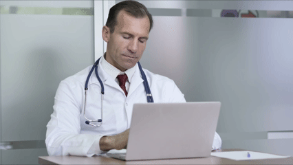 Tired overworked doctor on a laptop