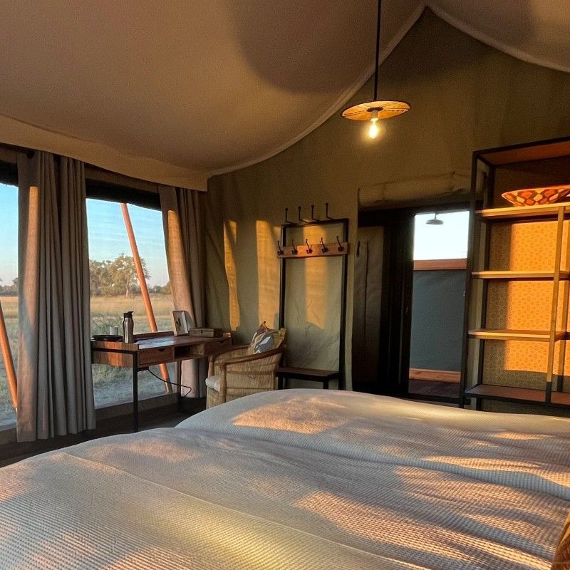 The interior of one of the tents at Karangoma in Botswana is showcased in this inviting travel photograph, highlighting a warm and thoughtfully designed space that blends comfort with the surrounding wilderness. A well-appointed bed and natural furnishings create a cozy, restful atmosphere, while soft neutral tones and subtle decorative touches echo the colors and textures of the bush outside. Large openings and canvas walls allow natural light and fresh air to fill the space, offering unobstructed views of the plains and wildlife nearby. The interior reflects a balance of understated luxury and authentic safari living, providing guests with a tranquil retreat immersed in Botswana’s natural environment. Inspiration Africa specializes in bespoke, tailor-made journeys to Botswana and across Africa, crafting unforgettable safari experiences in extraordinary wilderness destinations.