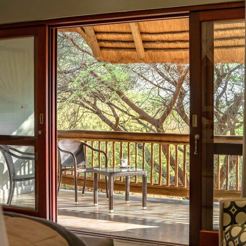 The balcony at Chobe Bush Lodge in Botswana is featured in this inviting travel photograph, overlooking the lush riverside landscape of the Chobe River. From the elevated vantage point, guests can enjoy uninterrupted views of the floodplains, dense vegetation, and wildlife that frequents the area, including elephants, hippos, and a variety of birds. Natural materials and understated design create a seamless connection between the lodge and its surroundings, offering a tranquil space to relax and immerse in the sights and sounds of the bush. The setting reflects a balance of comfort and authenticity, providing an intimate safari experience in one of Botswana’s most wildlife-rich regions. Inspiration Africa specializes in bespoke, tailor-made journeys to Botswana and across Africa, crafting unforgettable safari experiences in extraordinary wilderness destinations.