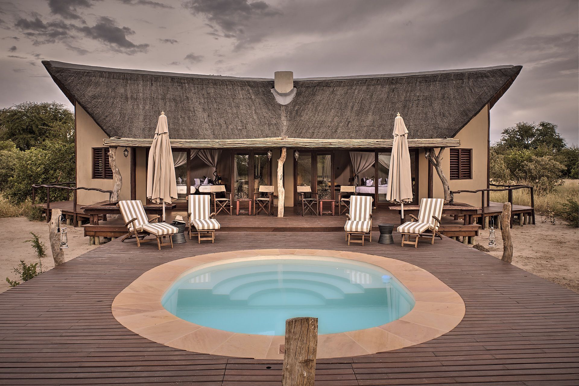 The swimming pool at Deception Valley Lodge in Botswana is captured in this serene travel photograph, set within the dramatic landscapes of the Kalahari Desert. The calm waters of the pool reflect the open skies and surrounding acacia trees, creating a tranquil oasis amid the vast, sandy expanse. Sun loungers and shaded areas invite relaxation, while the natural tones and simple design harmonize with the desert environment. The scene conveys peace, understated luxury, and a close connection to Botswana’s wild landscapes, highlighting Deception Valley Lodge as a peaceful retreat where guests can unwind while immersed in the beauty of the Kalahari. Inspiration Africa specializes in bespoke, tailor-made journeys to Botswana and across Africa, crafting unforgettable safari experiences in extraordinary destinations.