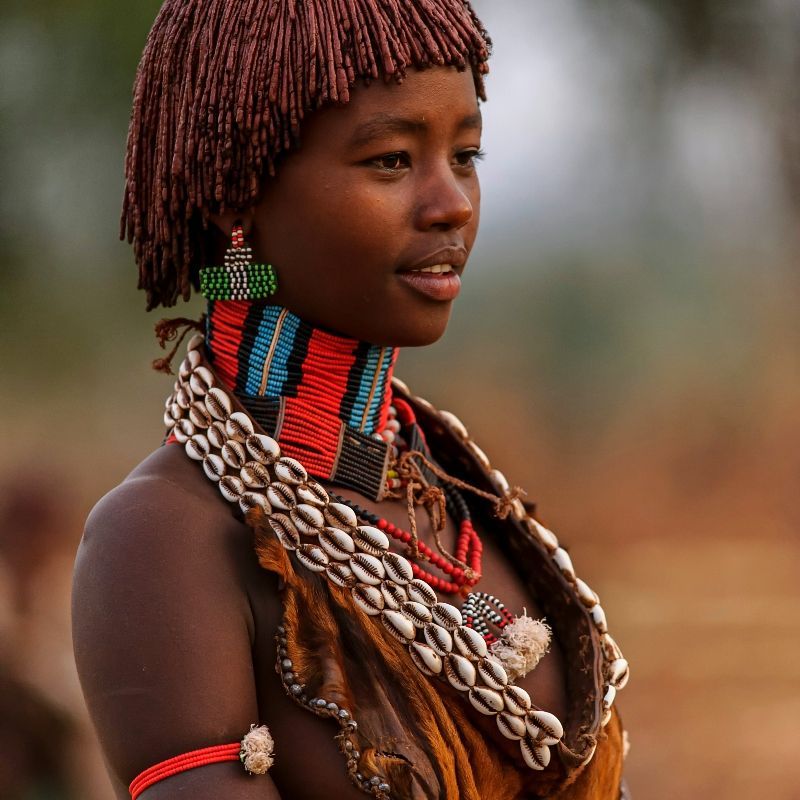 A Hamer woman from Ethiopia is shown adorned in traditional clothing and intricate jewelry, captured in this vibrant cultural travel photograph. Her colorful beads, bracelets, and ornaments reflect the rich heritage and unique customs of the Hamer people, one of Ethiopia’s most iconic indigenous communities. Set against the arid landscapes of the Omo Valley, this portrait highlights the artistry, identity, and cultural pride preserved through traditional dress, rituals, and daily life. Ideal for travelers interested in cultural immersion, photography, and authentic experiences, the image offers a window into Ethiopia’s extraordinary ethnic diversity. Inspiration Africa specializes in bespoke, tailor-made journeys to Ethiopia and across Africa, crafting authentic cultural encounters and unforgettable experiences in extraordinary destinations.