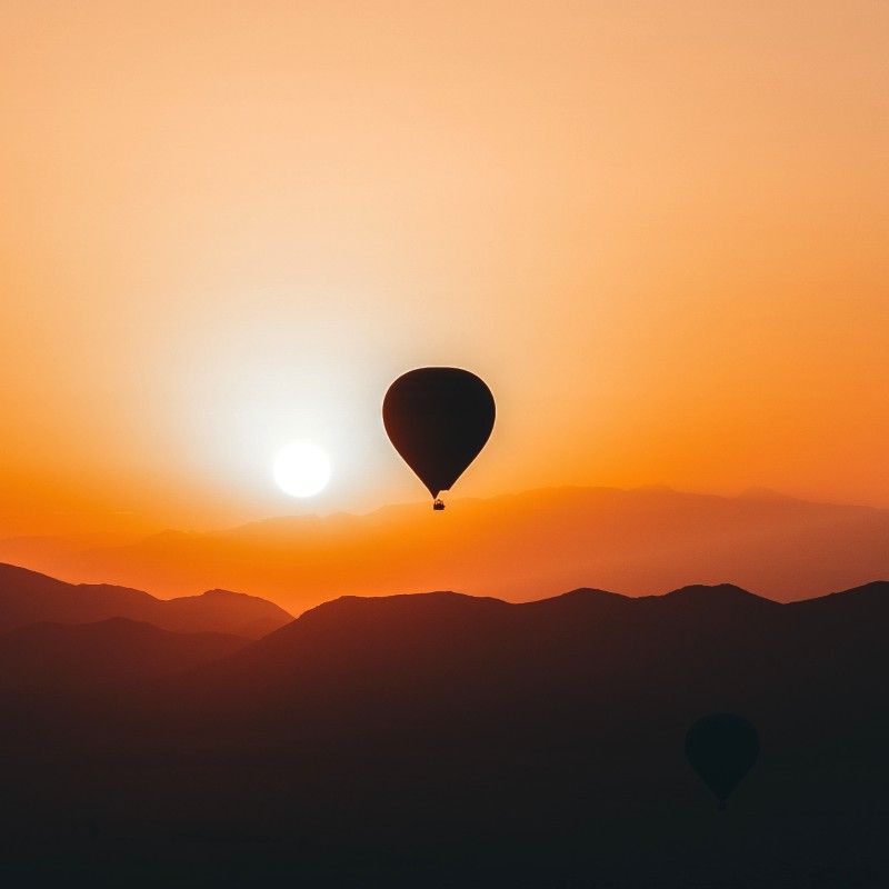 Gaze upon a spectacular balloon flight drifting above Marrakech and the surrounding desert during a glowing orange sunset. This striking photograph captures hot air balloons floating over arid plains and distant landscapes as the sky is bathed in warm amber and gold tones. The scene highlights the contrast between Morocco’s vast desert scenery and the timeless allure of Marrakech nearby. Experiencing a balloon flight at sunset offers a peaceful and unforgettable perspective on the region’s beauty, scale, and atmosphere. Inspiration Africa specializes in designing bespoke, tailor-made journeys that combine unique experiences with Africa’s most extraordinary landscapes and destinations.